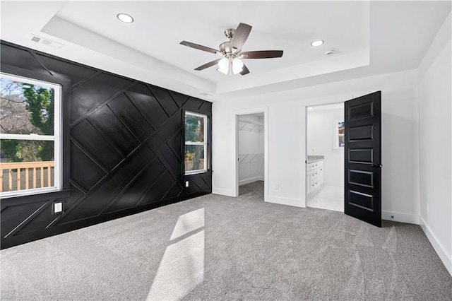 bedroom featuring multiple windows, a spacious closet, and a raised ceiling