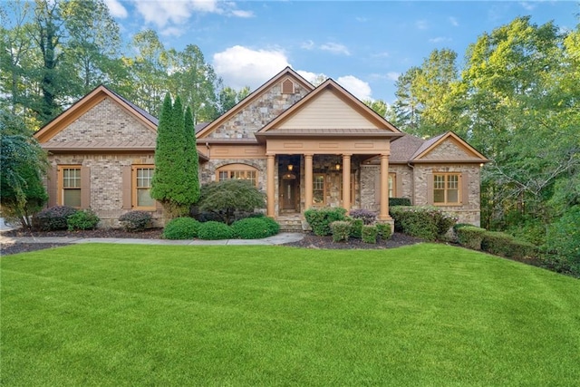 craftsman-style home featuring stone siding, a front lawn, and brick siding