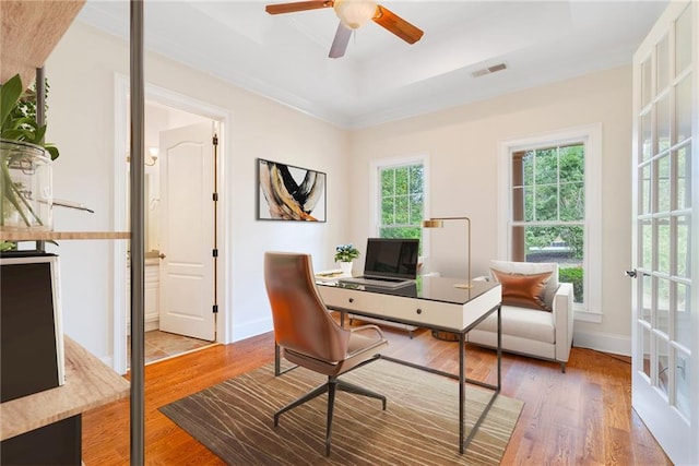 office space featuring a tray ceiling, visible vents, baseboards, and wood finished floors