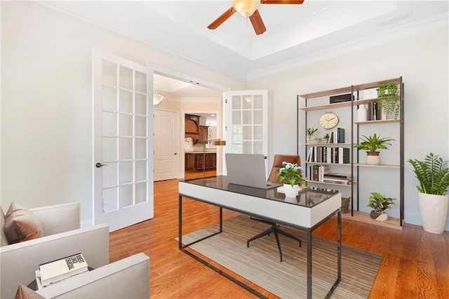 home office featuring ceiling fan, a raised ceiling, crown molding, and wood finished floors