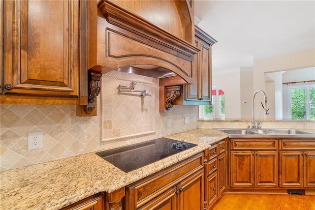 kitchen with tasteful backsplash, a sink, black electric cooktop, and brown cabinets