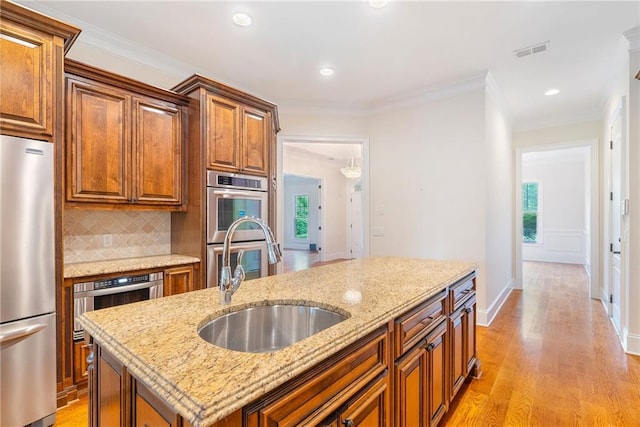 kitchen featuring tasteful backsplash, visible vents, light wood-style flooring, appliances with stainless steel finishes, and a sink