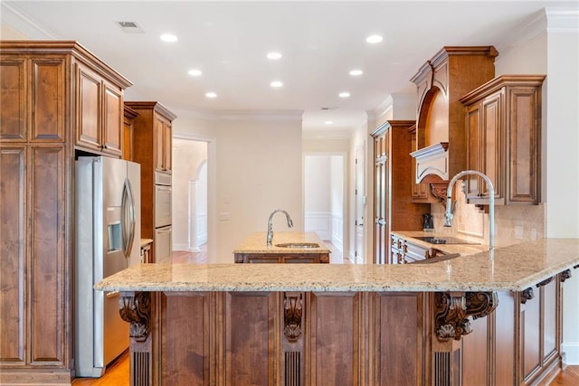 kitchen with visible vents, a kitchen island with sink, a sink, and stainless steel refrigerator with ice dispenser