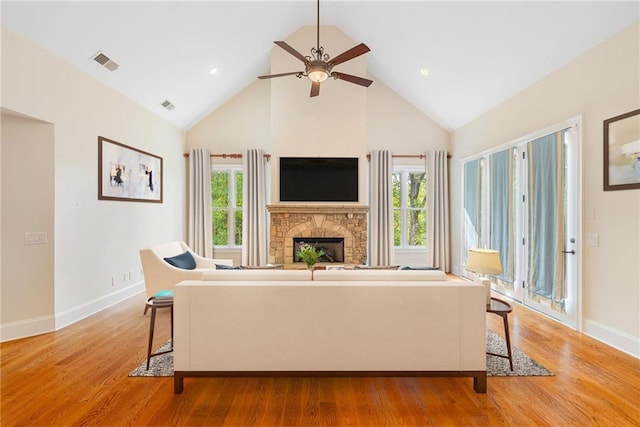 living area featuring a wealth of natural light, a fireplace, visible vents, and light wood-style floors