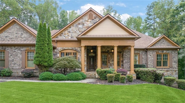 view of front of home with a shingled roof, brick siding, stone siding, a front lawn, and a standing seam roof