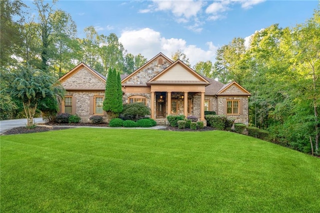 view of front of property featuring stone siding, a front lawn, covered porch, and brick siding