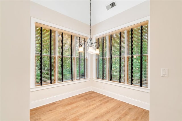 empty room with a wealth of natural light, light wood finished floors, visible vents, and baseboards