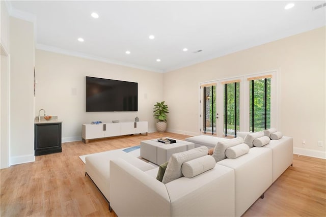 living area featuring baseboards, recessed lighting, light wood-type flooring, and crown molding