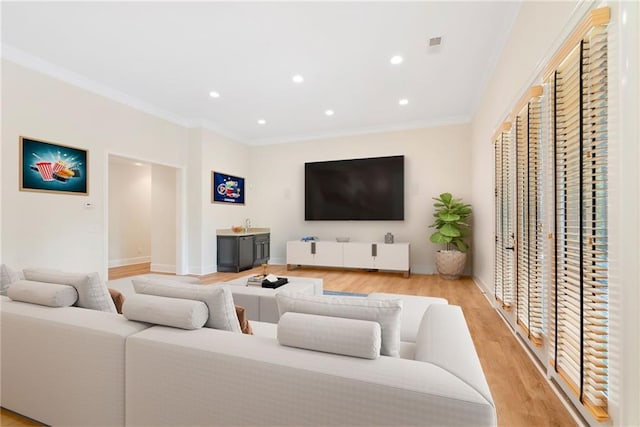 living area with visible vents, baseboards, crown molding, light wood-type flooring, and recessed lighting