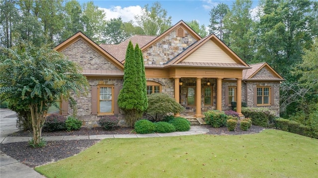 craftsman-style home featuring stone siding, a porch, a front yard, and brick siding