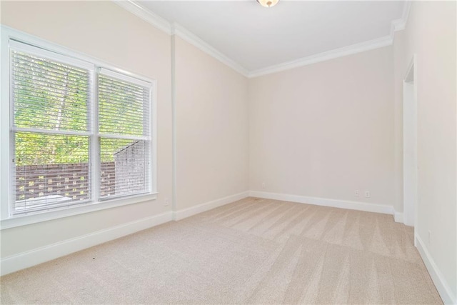 spare room featuring light colored carpet, crown molding, and baseboards