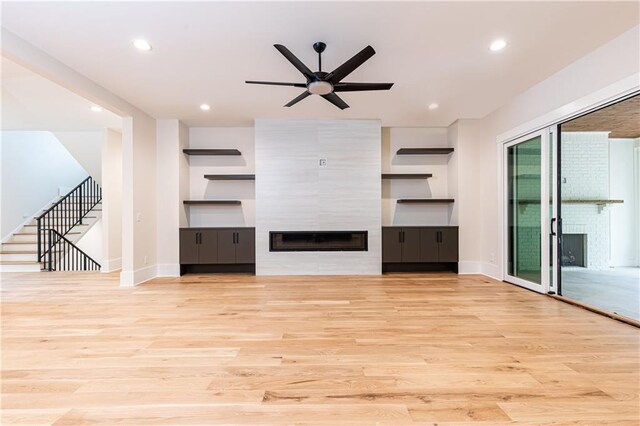 unfurnished living room featuring light hardwood / wood-style floors, ceiling fan, and a fireplace