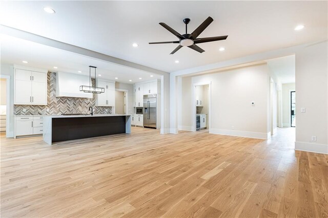 kitchen featuring white cabinets, hanging light fixtures, light hardwood / wood-style flooring, ceiling fan, and stainless steel built in refrigerator