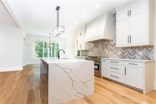 kitchen featuring white cabinetry, custom range hood, and stainless steel stove