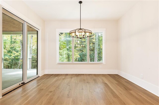 empty room featuring light wood-type flooring and a chandelier