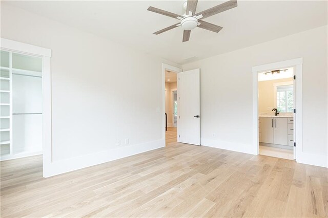 unfurnished bedroom featuring light wood-type flooring, ceiling fan, connected bathroom, and sink