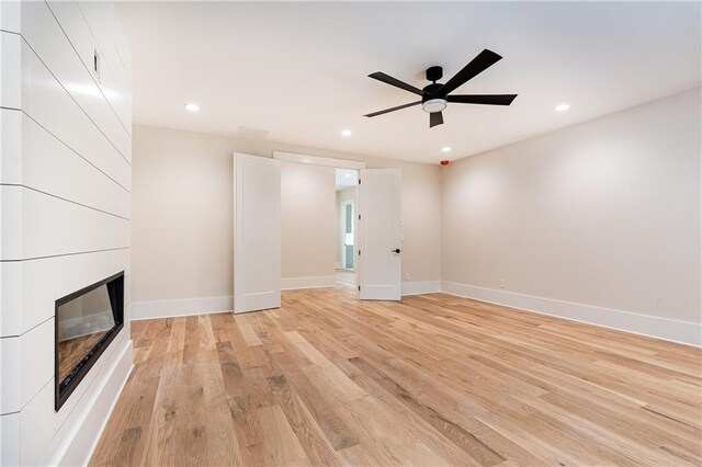 unfurnished living room featuring light hardwood / wood-style flooring, ceiling fan, and a fireplace