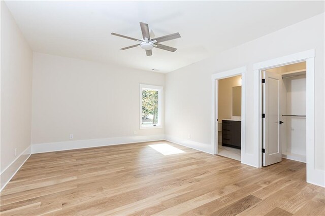 unfurnished bedroom with light hardwood / wood-style flooring, ensuite bath, a walk in closet, and ceiling fan