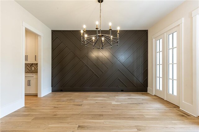 unfurnished dining area featuring a healthy amount of sunlight, light hardwood / wood-style flooring, and an inviting chandelier