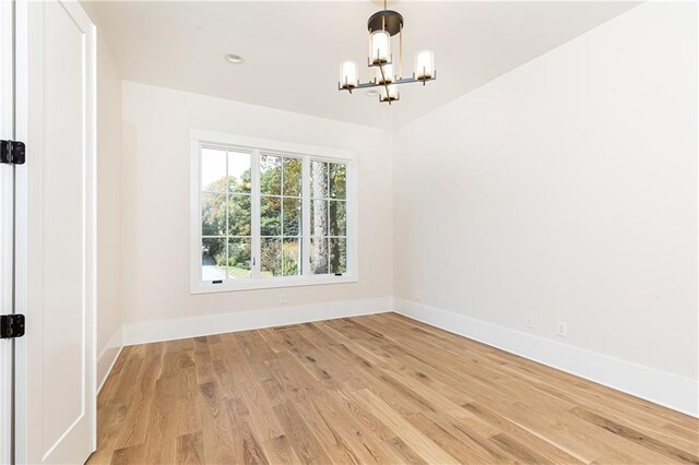 spare room featuring light hardwood / wood-style flooring and a notable chandelier