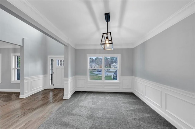 unfurnished dining area with a healthy amount of sunlight, wainscoting, and crown molding