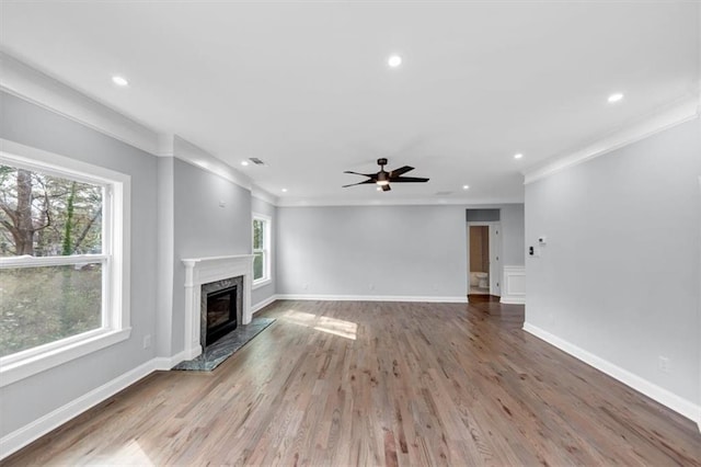 unfurnished living room featuring baseboards, ornamental molding, a fireplace, wood finished floors, and a ceiling fan