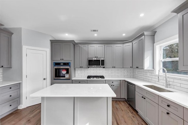 kitchen featuring a sink, backsplash, appliances with stainless steel finishes, and gray cabinets