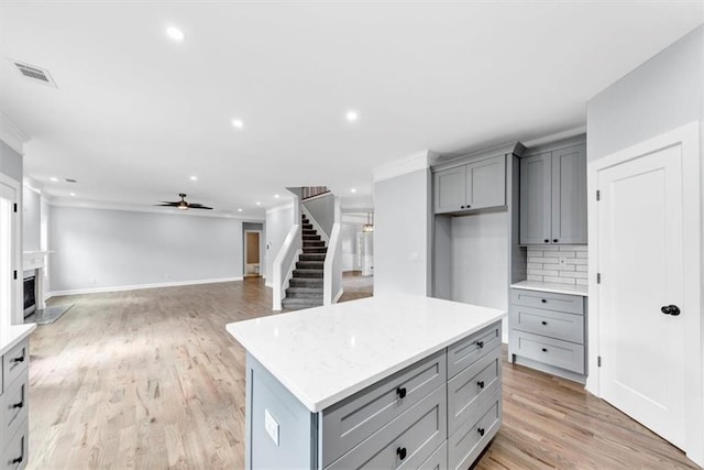 kitchen with light wood-style flooring, recessed lighting, gray cabinets, ceiling fan, and decorative backsplash