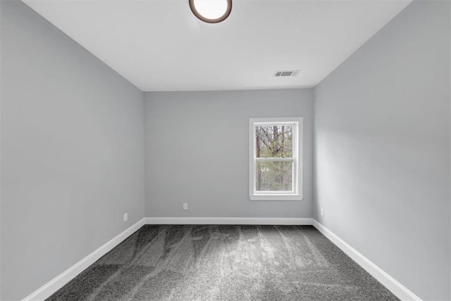 spare room featuring visible vents, dark carpet, and baseboards