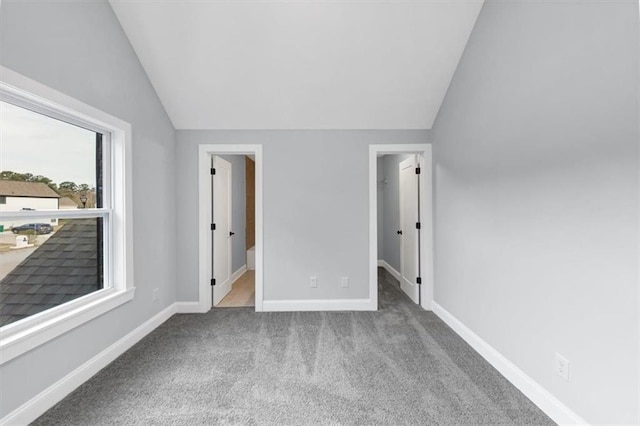 unfurnished bedroom with baseboards, lofted ceiling, a spacious closet, and carpet flooring