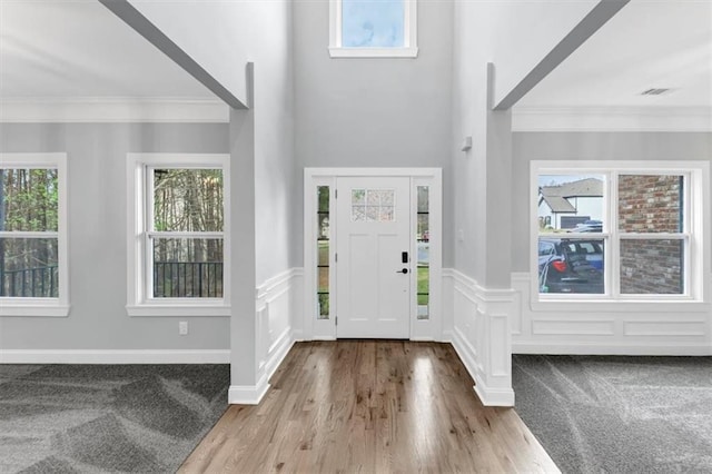 entrance foyer with plenty of natural light, wainscoting, wood finished floors, and ornamental molding