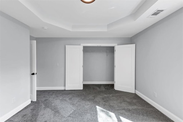 unfurnished bedroom with visible vents, baseboards, a raised ceiling, and carpet