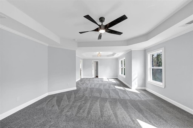 carpeted spare room with visible vents, crown molding, baseboards, ceiling fan, and a raised ceiling