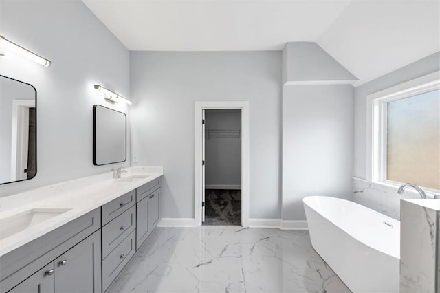 full bath featuring a sink, baseboards, a freestanding bath, and marble finish floor