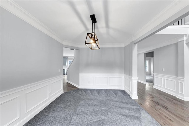 unfurnished dining area featuring a wainscoted wall, wood finished floors, ornamental molding, and a decorative wall