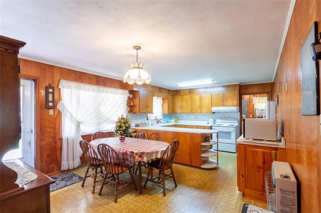 dining area featuring wooden walls, light floors, crown molding, and a chandelier
