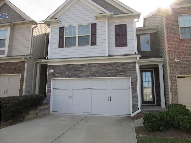 view of front of property featuring an attached garage, stone siding, and concrete driveway