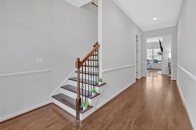 staircase featuring wood-type flooring and crown molding