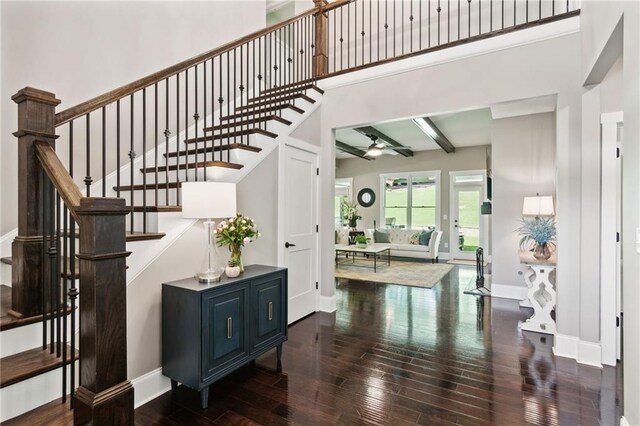 stairs featuring hardwood / wood-style flooring, beamed ceiling, and a high ceiling