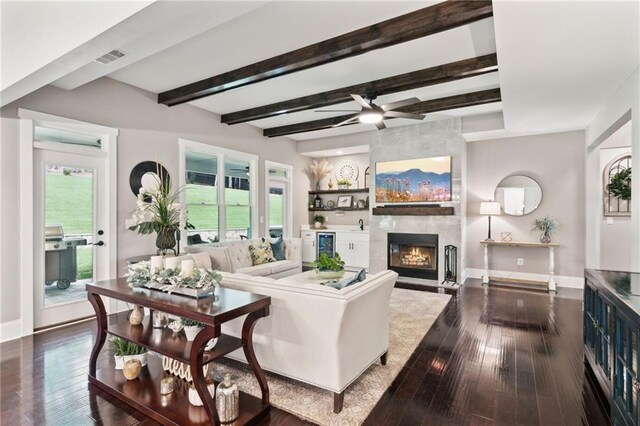 living room featuring beam ceiling, wood-type flooring, a fireplace, and ceiling fan