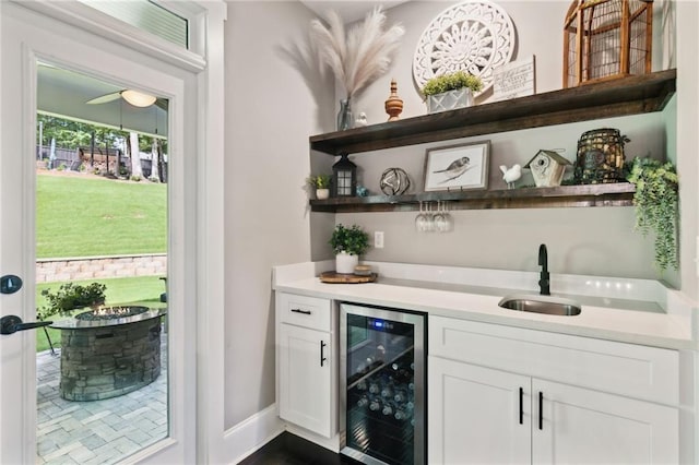 bar featuring white cabinets, sink, and beverage cooler