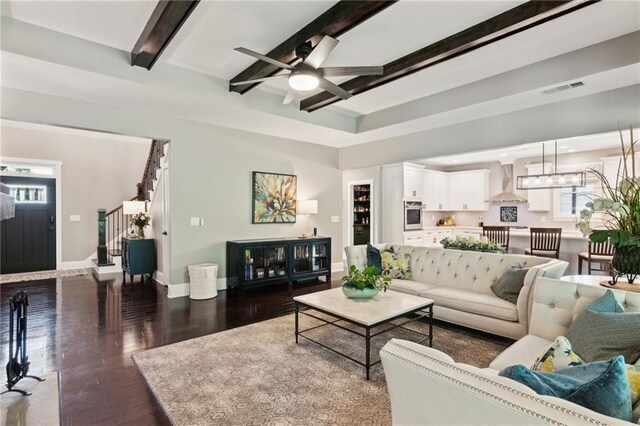 living room with beam ceiling, dark hardwood / wood-style flooring, and ceiling fan