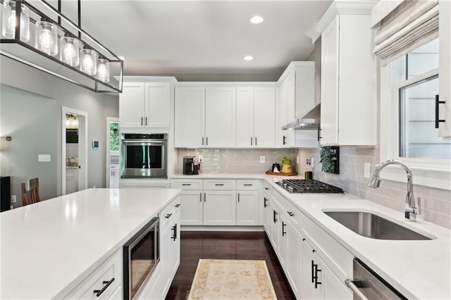 kitchen featuring wall chimney range hood, appliances with stainless steel finishes, sink, and white cabinets