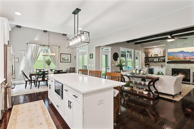 kitchen with dark hardwood / wood-style flooring, a kitchen island, white cabinetry, pendant lighting, and stainless steel appliances