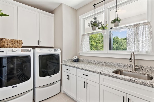 clothes washing area featuring cabinets, sink, washing machine and clothes dryer, and light tile patterned floors