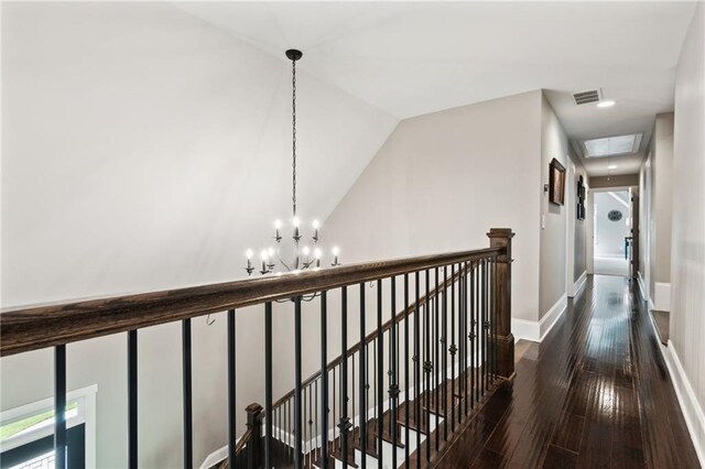 corridor featuring a notable chandelier, dark hardwood / wood-style floors, and vaulted ceiling