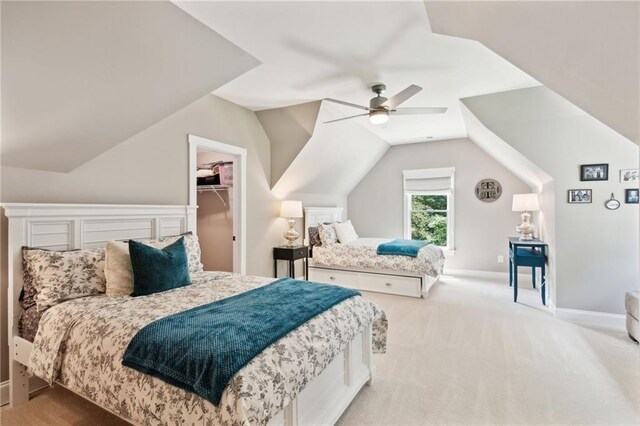 carpeted bedroom featuring a walk in closet, a closet, vaulted ceiling, and ceiling fan