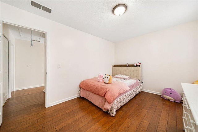 bedroom with baseboards, attic access, dark wood-style floors, and visible vents