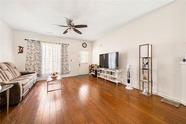 living room featuring a ceiling fan, a textured ceiling, wood finished floors, and baseboards