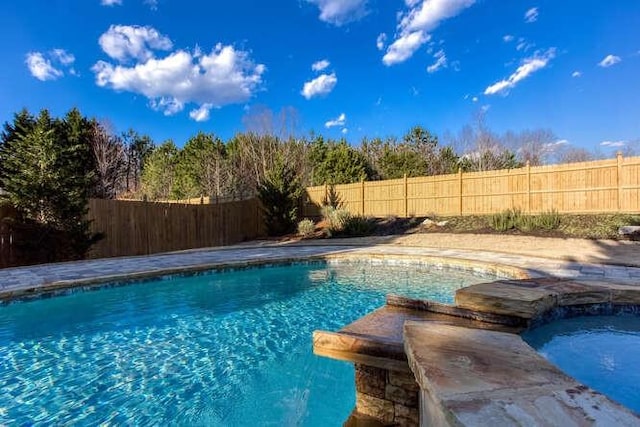 view of pool with a fenced backyard and a pool with connected hot tub